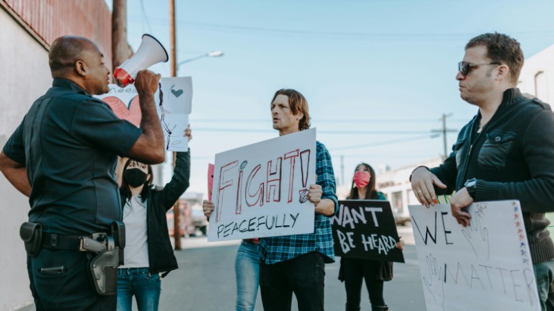 A peaceful protest with diverse individuals and police interaction, emphasizing unity and civil rights., tags: de van - pexel